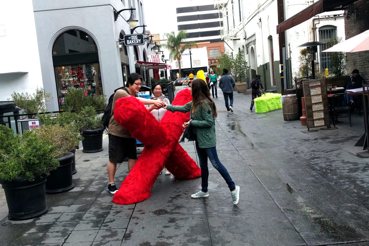 three people looking at a red x fur sculpture